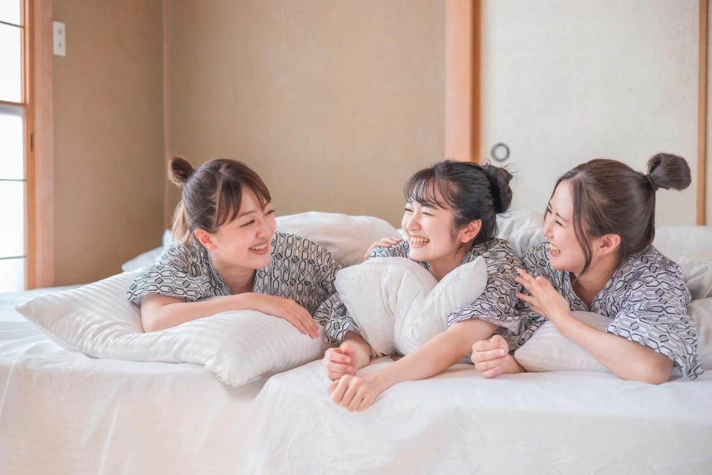 three women are laying on a bed at Yawarano-yu MARUYA For women only in Ise