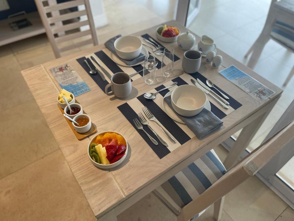 a table with plates and bowls of food on it at Gull on the Bay Boutique Guest House in Bloubergstrand