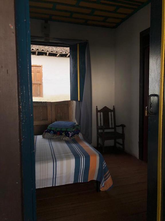a bedroom with a bed with a window and a chair at Hostal Salento Sunset in Salento