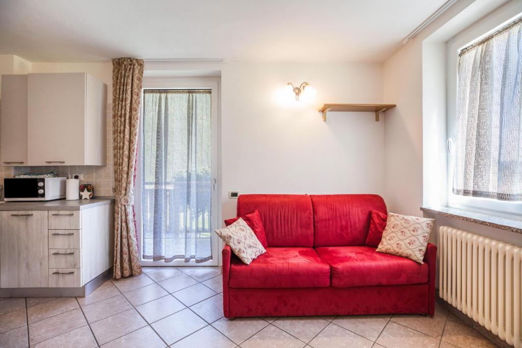 a red couch in a living room with a kitchen at Casa Penasa appartamento 2 in Commezzadura
