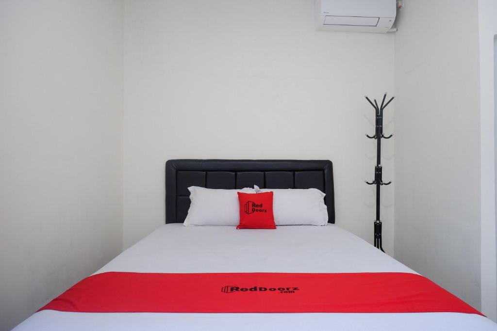 ein rotes Kissen auf einem weißen Bett in einem Zimmer in der Unterkunft RedDoorz Syariah near RS Soeradji Pemuda Klaten in Klaten