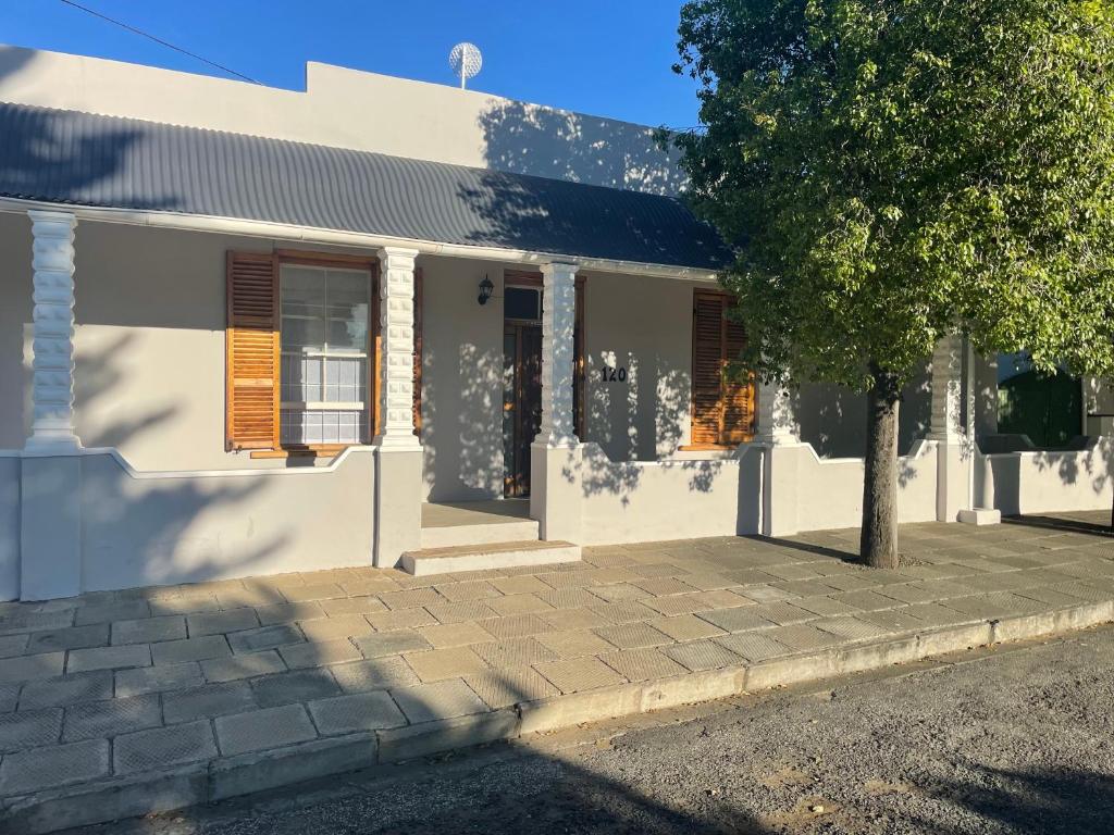 a white house with a tree in front of it at Back Home Bed and Breakfast in Graaff-Reinet