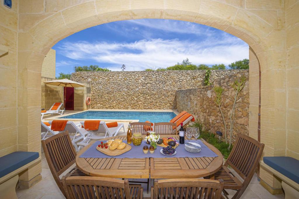 a patio with a table and chairs and a pool at Narcisa Holiday Home in Nadur