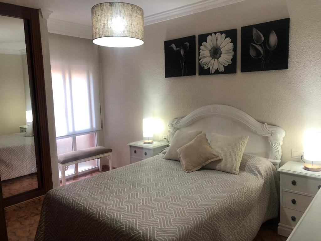 - une chambre dotée d'un lit blanc avec deux tables et deux lampes dans l'établissement Piso en Pedregalejo a 50m de la playa., à Malaga