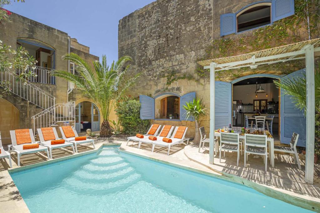 - une piscine avec des chaises et une table à côté d'un bâtiment dans l'établissement Oleandra Holiday Home, à Għasri