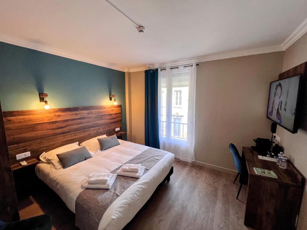 a bedroom with a large bed with a wooden headboard at Logis Hôtel Spa la Poste in Vitry-le-François