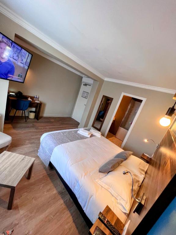a bedroom with a large bed and a flat screen tv at Logis Hôtel Spa la Poste in Vitry-le-François