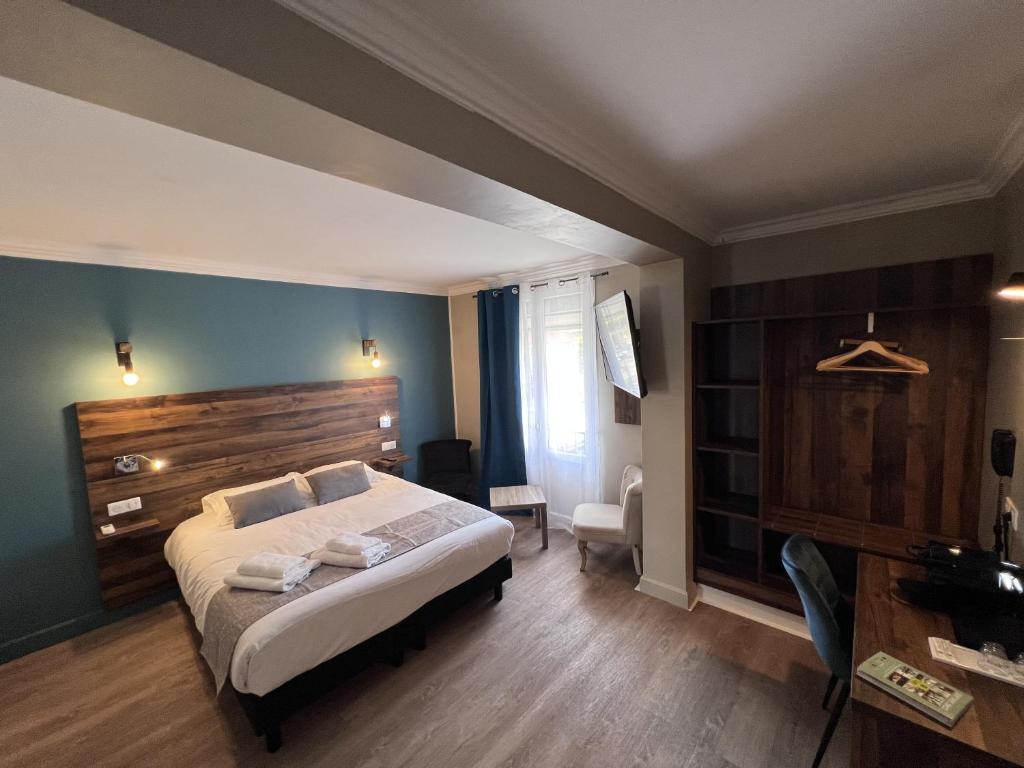 a bedroom with a large bed with a wooden headboard at Logis Hôtel Spa la Poste in Vitry-le-François