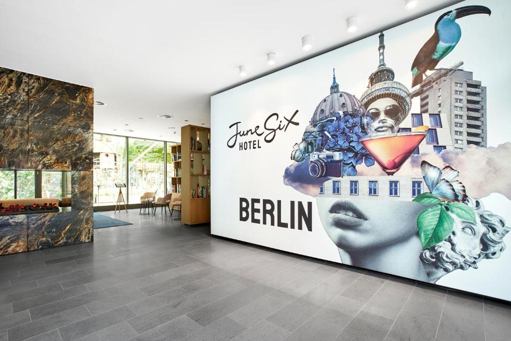 a lobby with a large wall mural of a woman with a head at June Six Hotel Berlin City West in Berlin