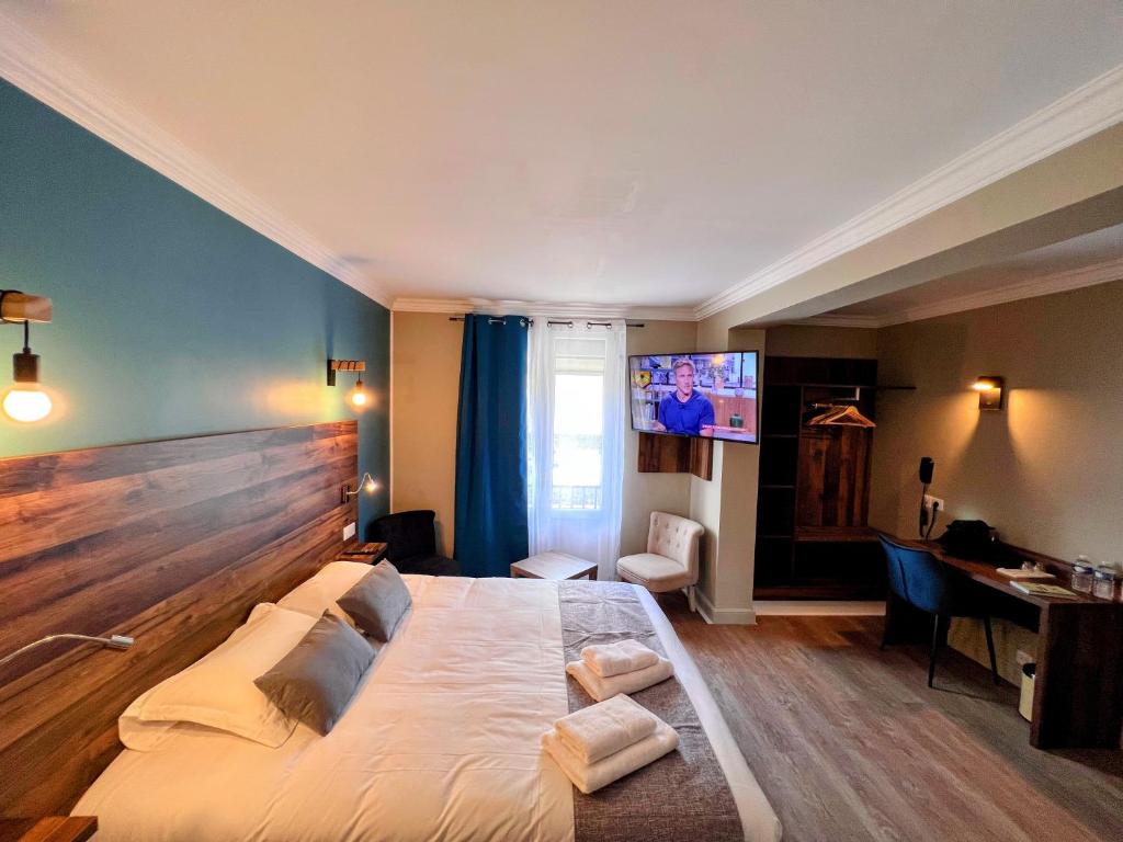 a bedroom with a large bed and a tv at Logis Hôtel Spa la Poste in Vitry-le-François