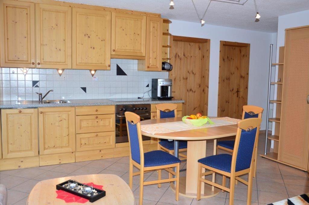 eine Küche mit einem Holztisch, Stühlen und einem Tisch in der Unterkunft Villa Kuntner Bund in Tschierv