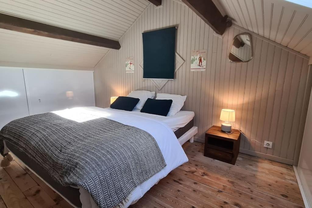 um quarto com uma cama grande e uma mesa com um candeeiro em La Fario - Grande maison familiale em Font Romeu Odeillo Via