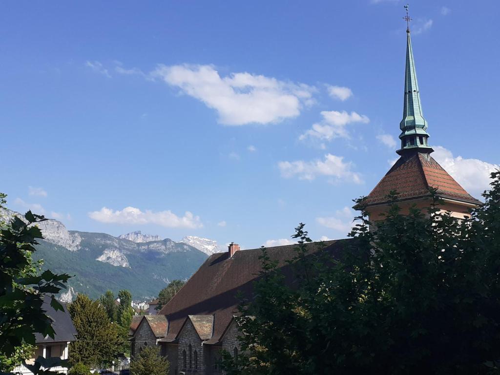 uma igreja com um campanário com uma montanha ao fundo em Zoulysse III Annecy em Annecy