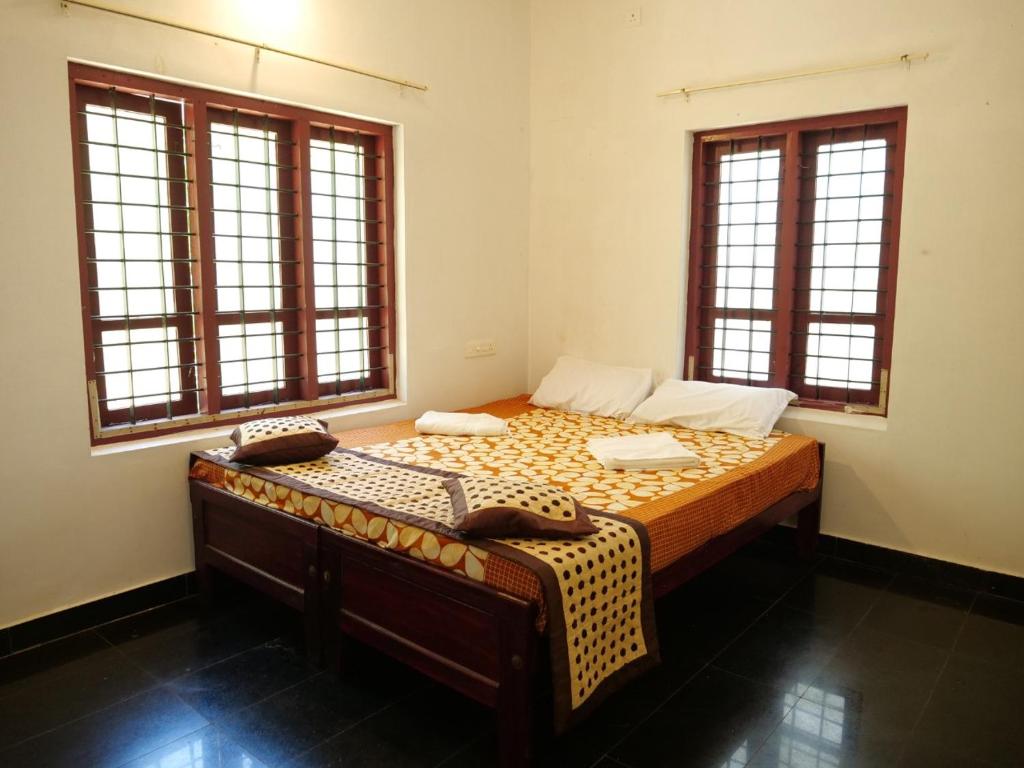 a bedroom with a large bed with two windows at Secret Paradise in Varkala