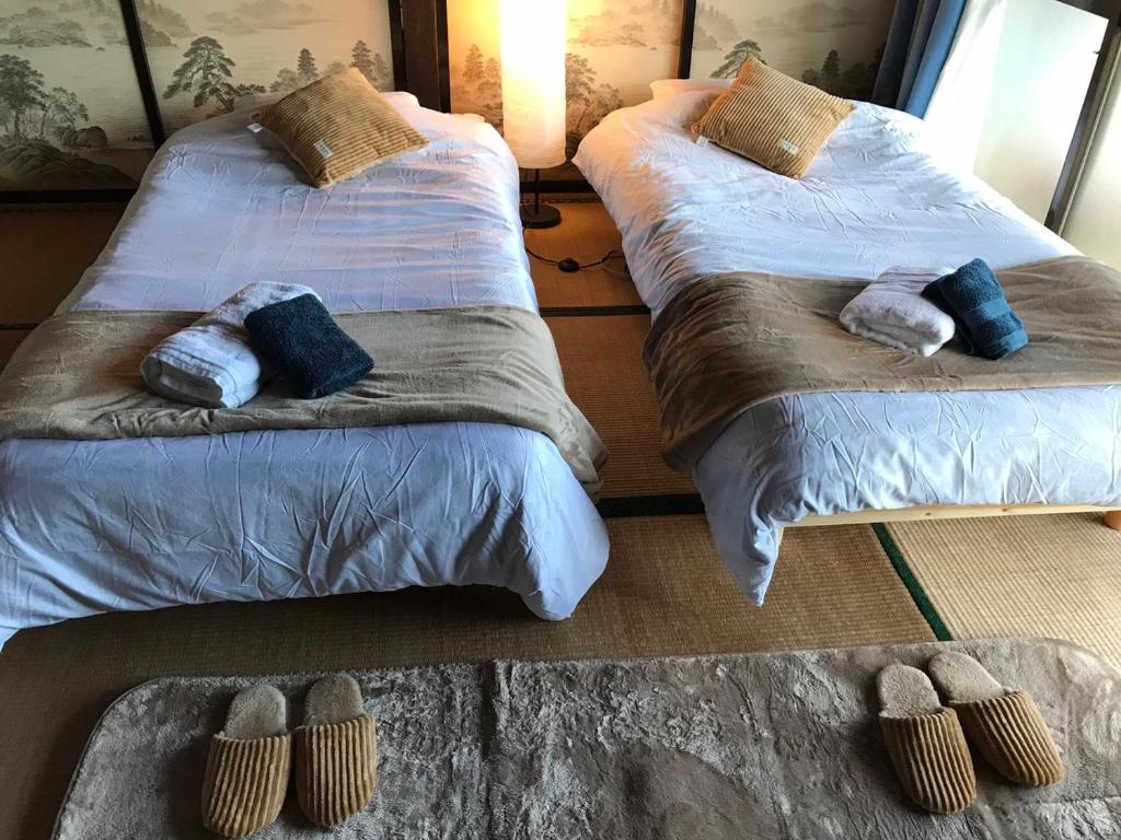two beds in a room with slippers on the floor at Astuto Riders House in Annaka