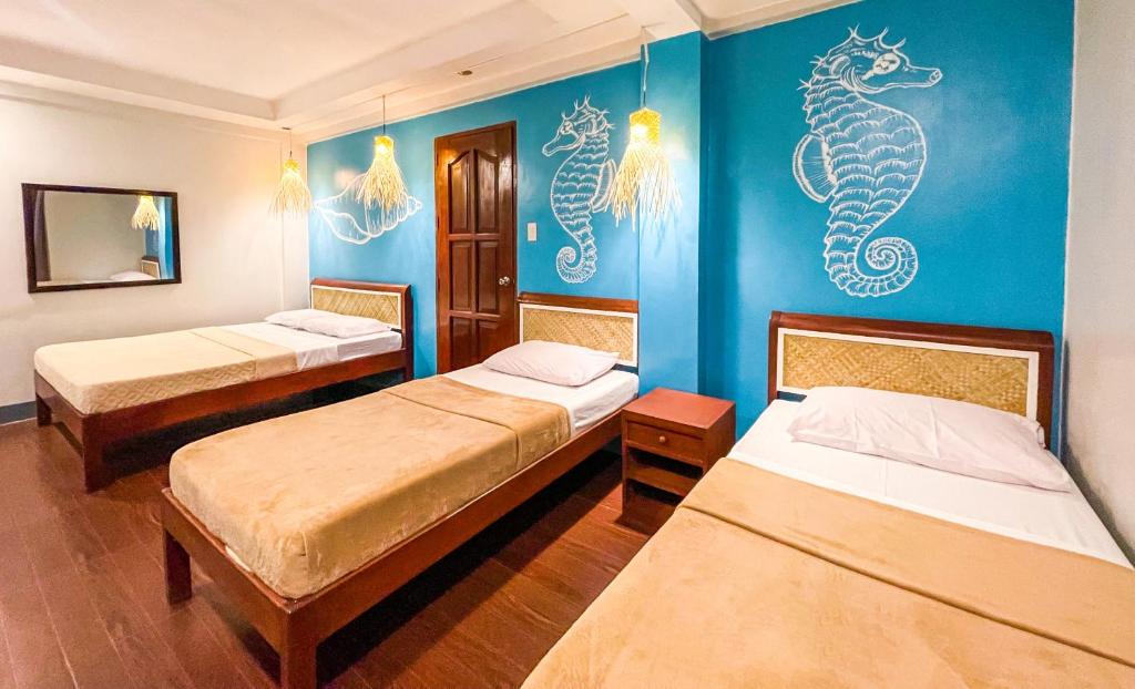 um quarto com 2 camas e uma parede de cavalo marinho em Amos Portside Inn em El Nido