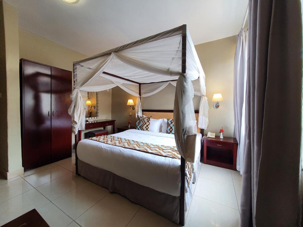 a bedroom with a large bed with a canopy at Serendib Suites and Conference Center in Blantyre