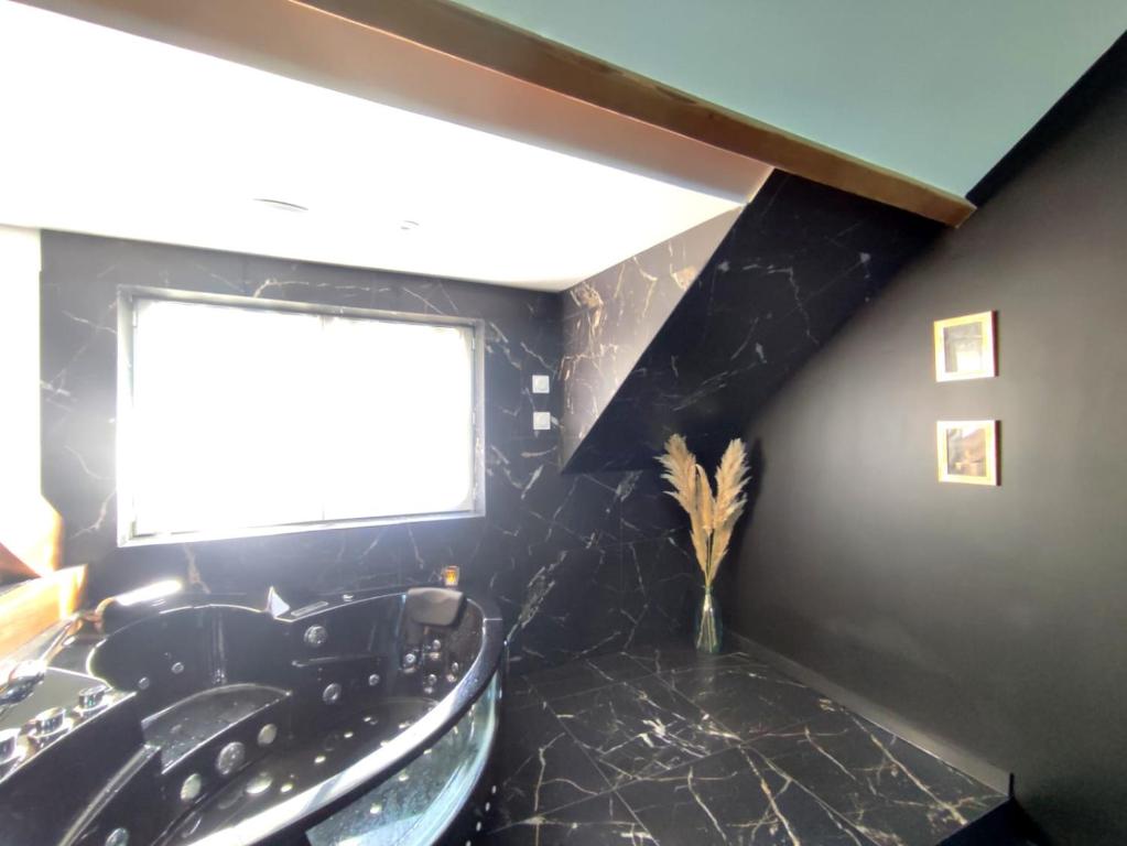 La salle de bains est pourvue d'une baignoire noire et d'une fenêtre. dans l'établissement Love Room à Montargis, à Montargis