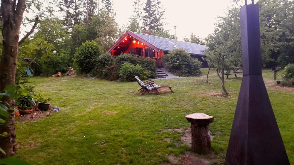 una casa roja con un banco en un patio en Chalet Barvaux met grote tuin, en Durbuy