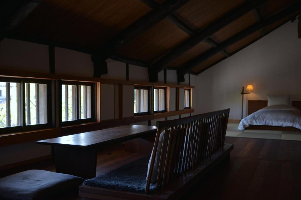 Habitación con mesa de madera y cama en 滔々 倉敷民藝館南の宿 toutou, Mingeikan Minami no Yado, en Kurashiki