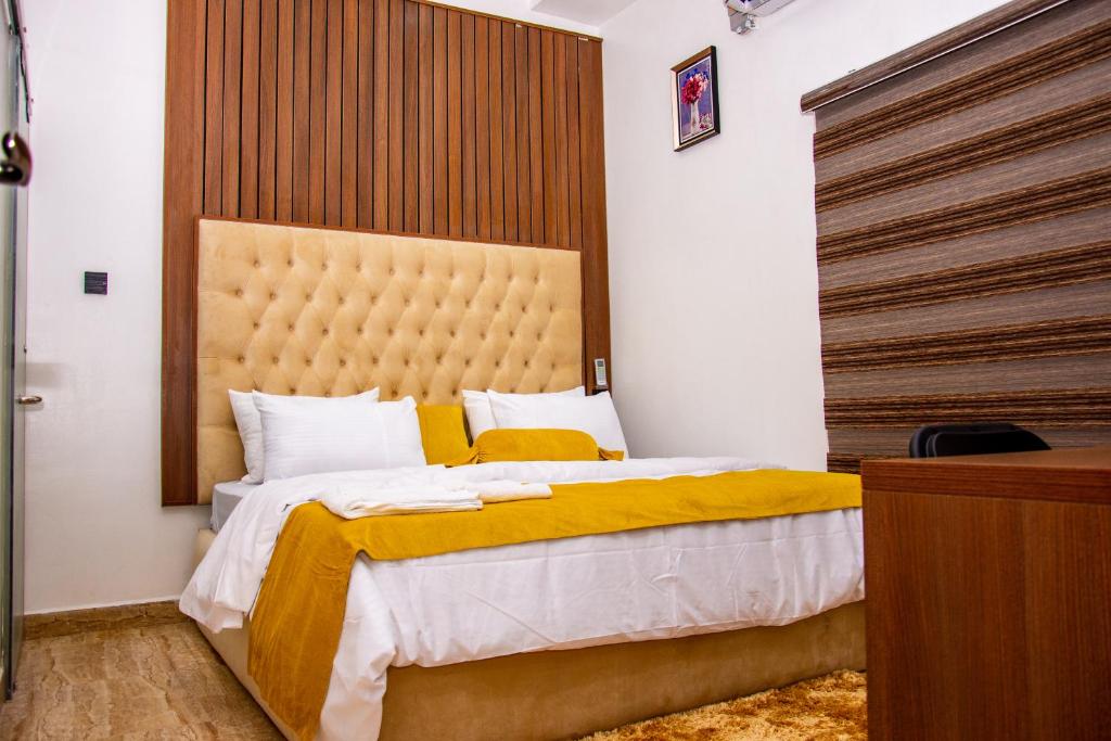 een slaapkamer met een groot bed met een gele deken bij NIFEWAT APARTMENT,Bris suite 1bedroom apartment gym, Netflix,WiFi in Abuja