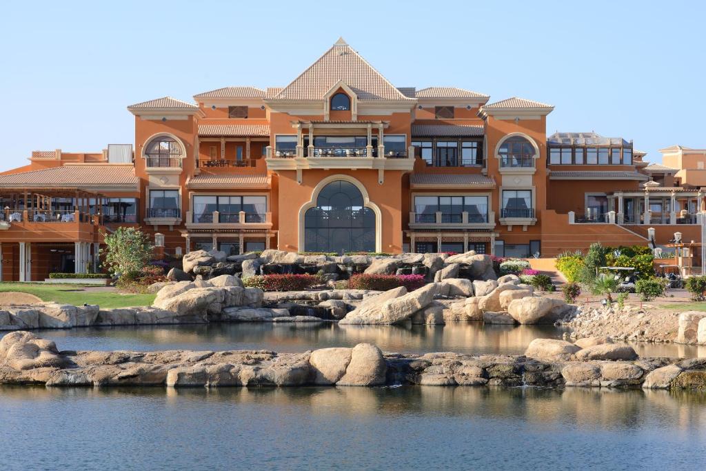 a house on the water with rocks in front of it at The Cascades Golf Resort, Spa & Thalasso in Hurghada