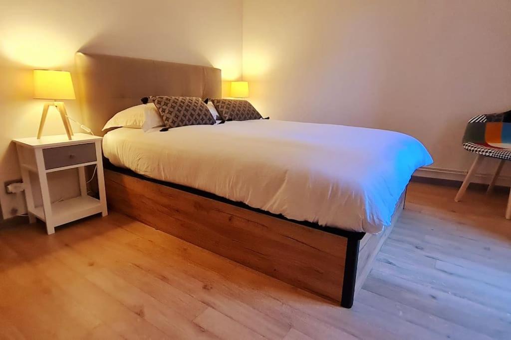 um quarto com uma cama grande e piso em madeira em Le 56 Faubourg - Proche centre - Parking gratuit em Beaune