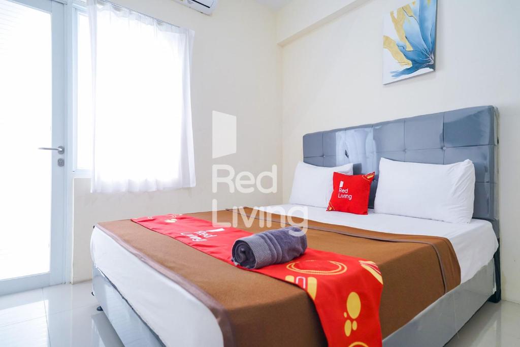 ein Schlafzimmer mit einem Bett mit roten Kissen darauf in der Unterkunft RedLiving Apartemen Bogorienze Resort - Skyland Tower A in Bogor
