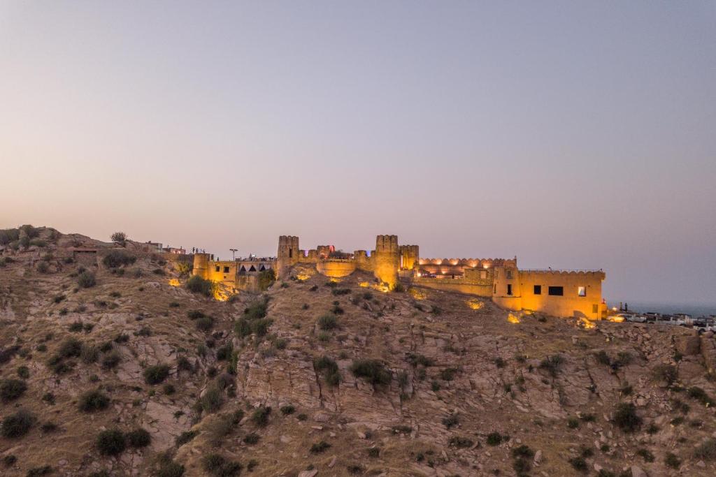 un château au sommet d'une montagne la nuit dans l'établissement Mundota Fort And Palace, à Pachār