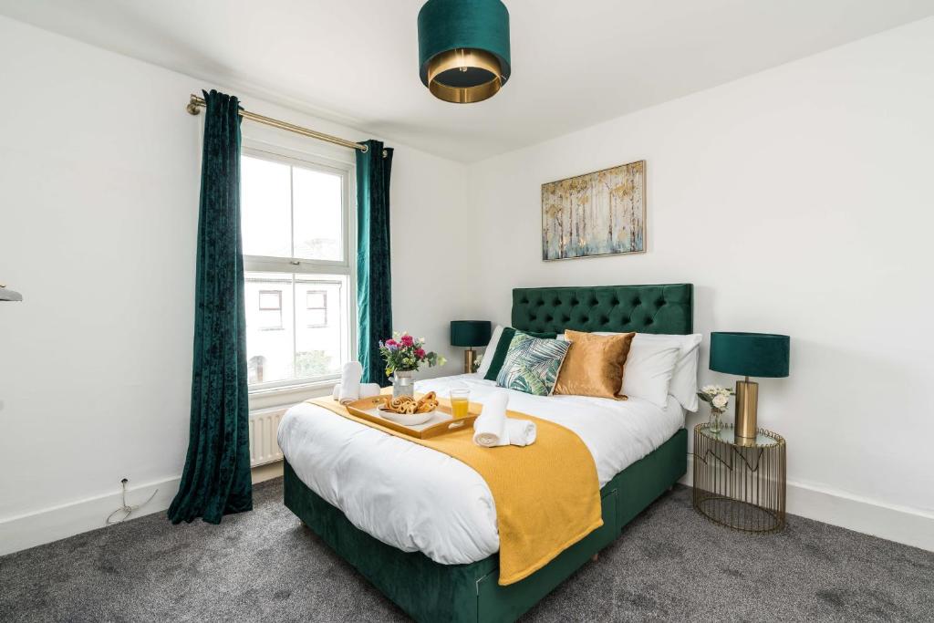 a bedroom with a large bed with a green headboard at Dressed to impress 2 bed house in Heart of Croydon ID Required in Croydon