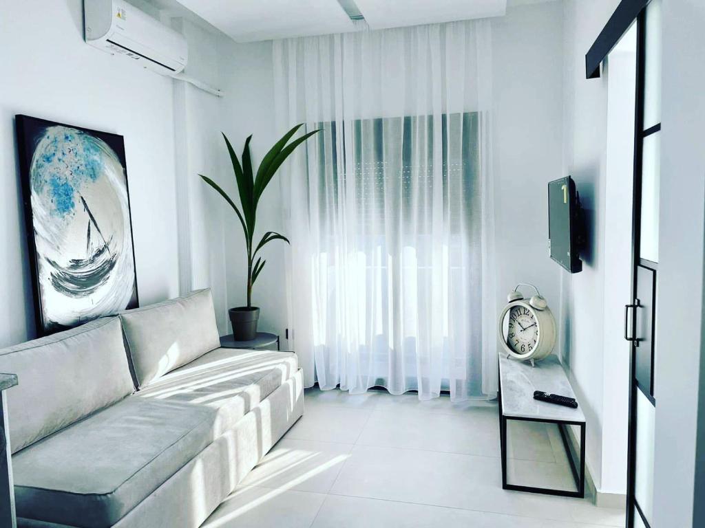 a white living room with a couch and a clock at Noi leisure stay 3 in Neoi Epivates