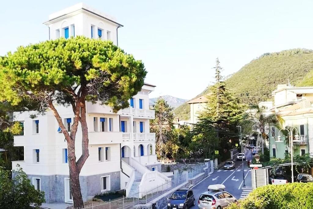 un edificio bianco con un albero accanto a una strada di Villa Schiaffino Appartamento al Primo Piano a Deiva Marina