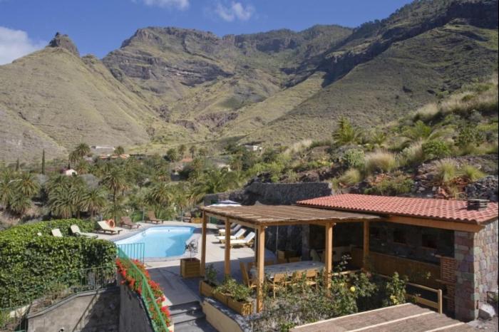 a house with a swimming pool and mountains in the background at Casa rural en el Risco de Agaete A in Agaete