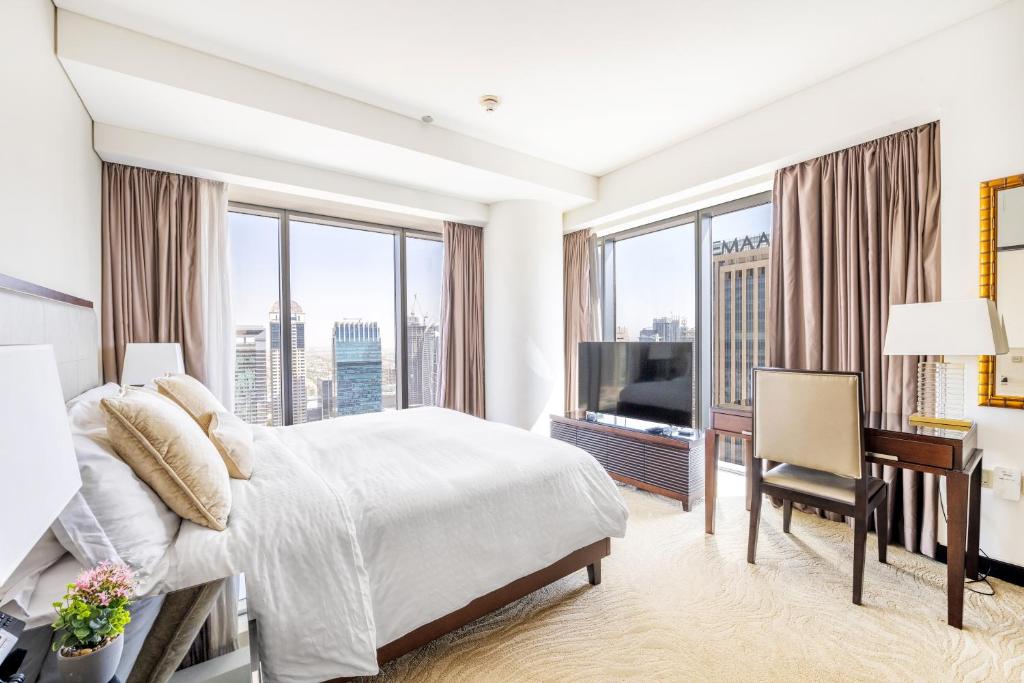 a bedroom with a large bed and a desk with a desk at Address Dubai Marina - 1B Apt, Full Marina View with 5 Star Hotel Facilities by Gardenia Suites in Dubai