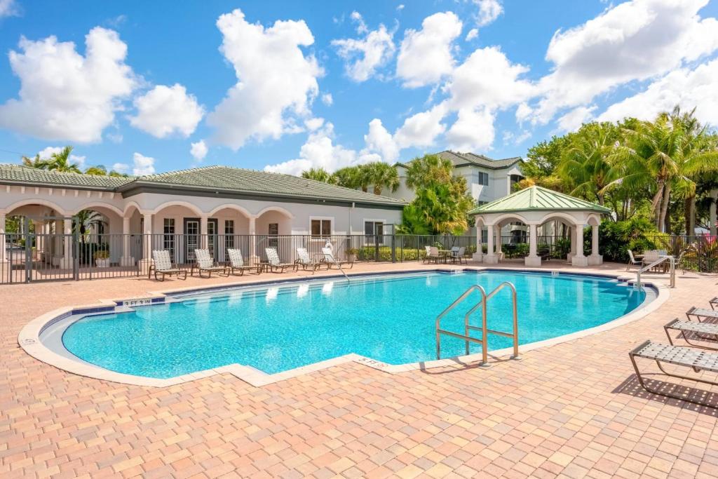 戴維的住宿－Bright and Modern Apartments at Palm Trace Landings in South Florida，一个带椅子的游泳池以及一座房子