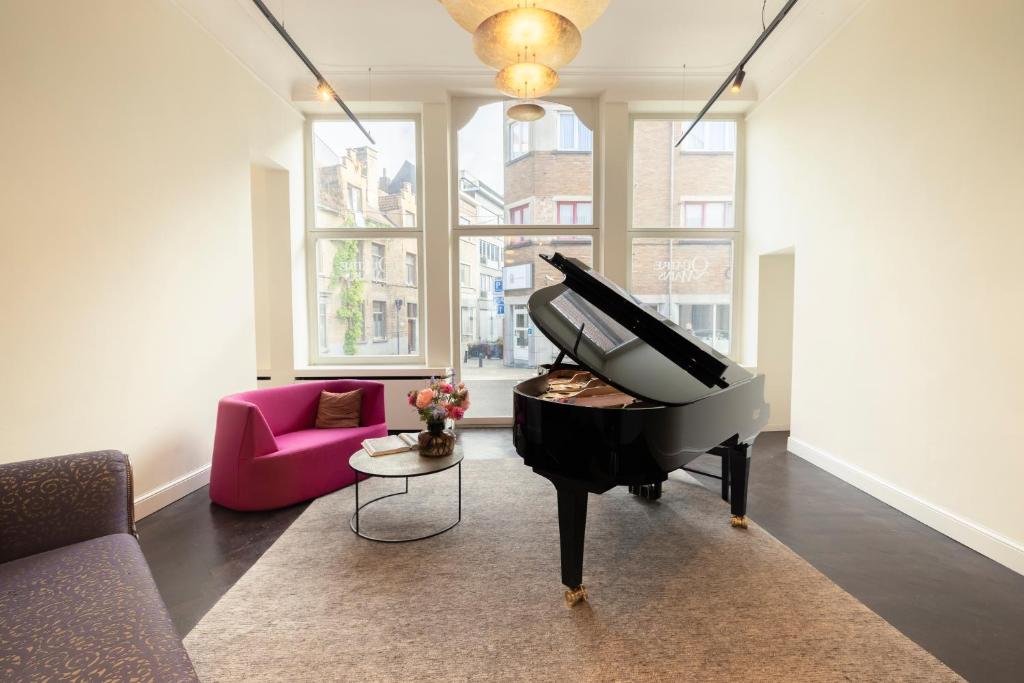 a piano in a living room with a pink couch at B&B Kwaadham 52 - Music Hotel Ghent in Ghent