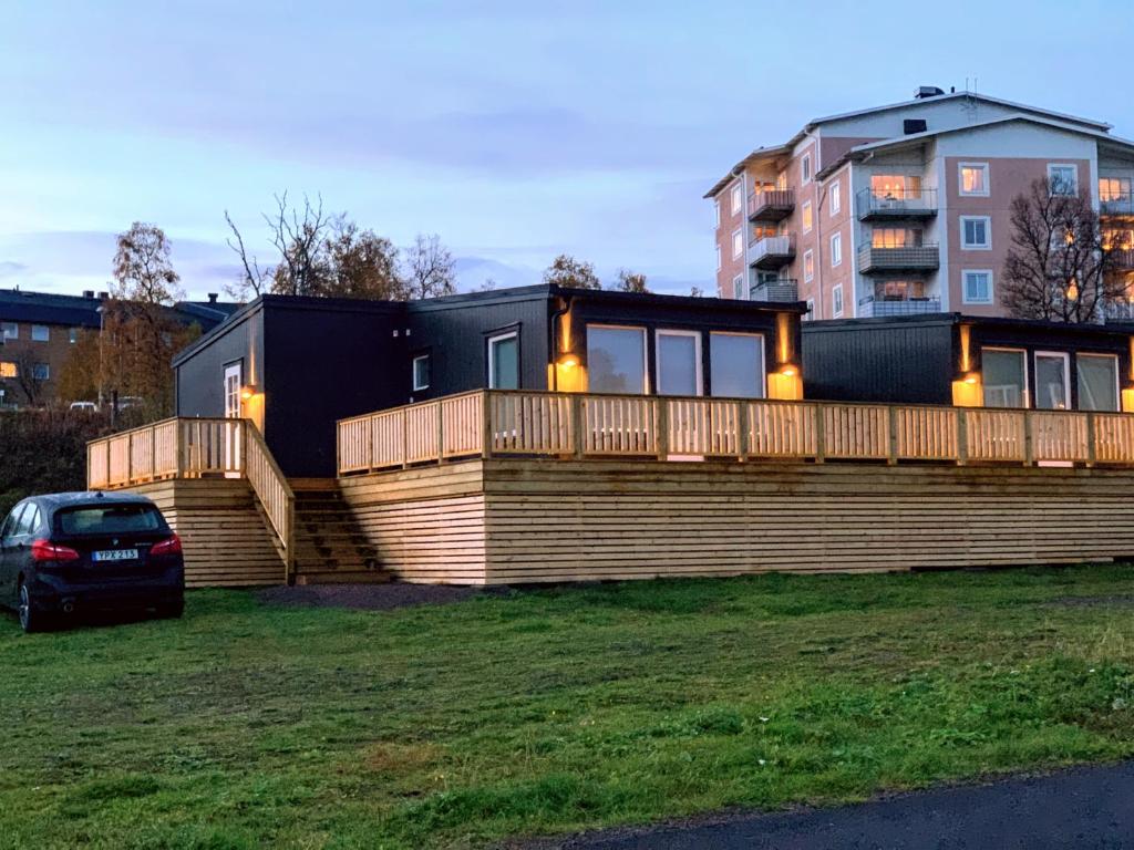 une maison avec une grande terrasse et une voiture sur l'herbe dans l'établissement Private Chalet with Sauna, à Kiruna