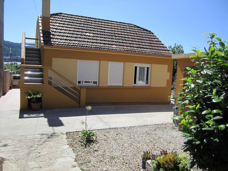 a small yellow house with a staircase on it at Casita con terreno a 10 minutos del centro de Vigo in Moaña