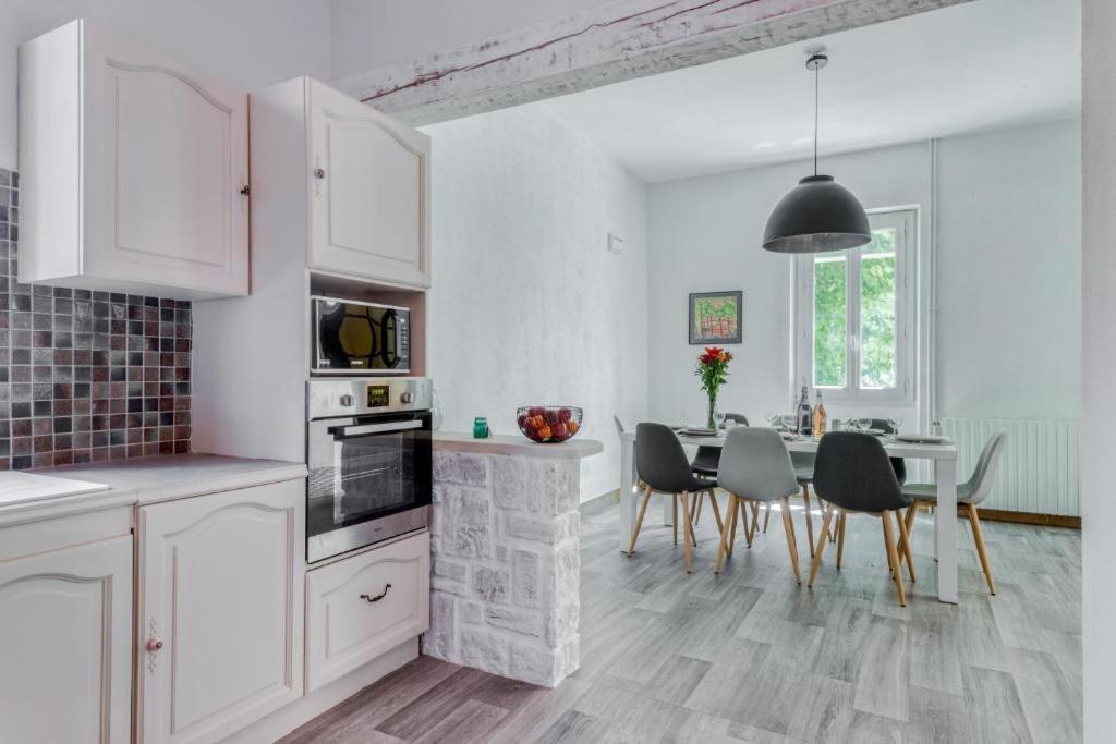 a kitchen with white cabinets and a table and chairs at L&#39;Ardeche en Provence avec jardin ombragé in Pont-Saint-Esprit