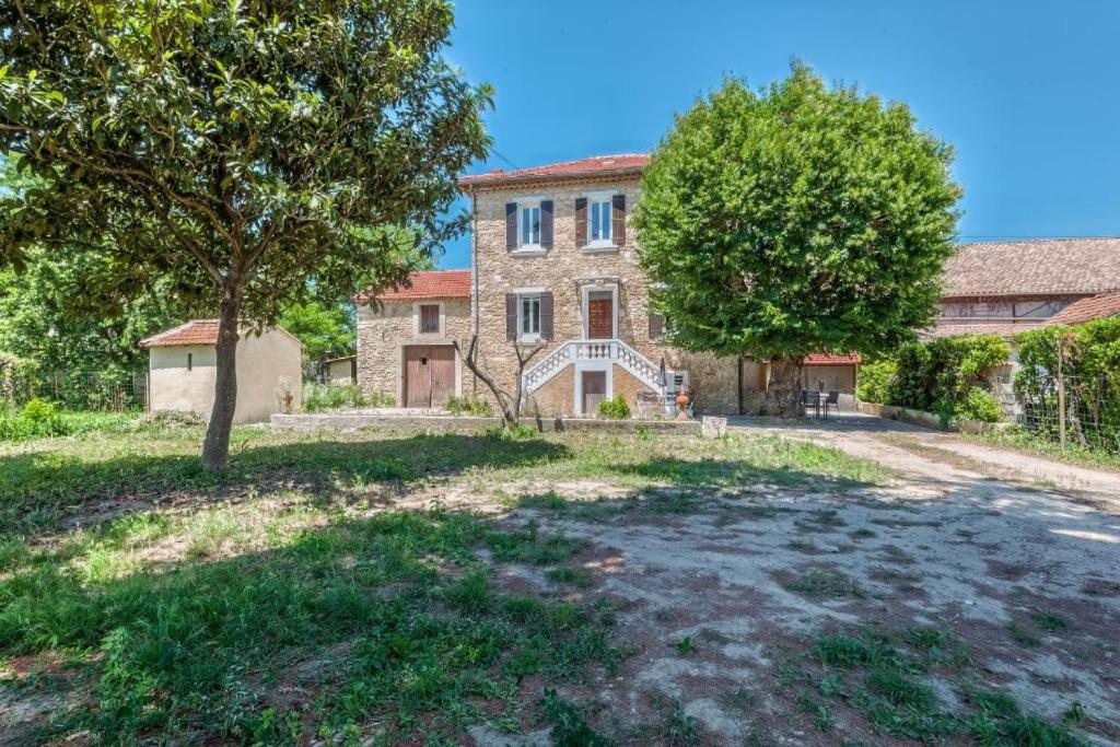 an old stone house with a tree in front of it at L&#39;Ardeche en Provence avec jardin ombragé in Pont-Saint-Esprit