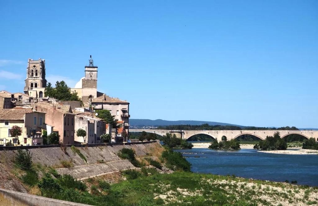 a building on a hill next to a river with a bridge at L&#39;Ardeche en Provence avec jardin ombragé in Pont-Saint-Esprit