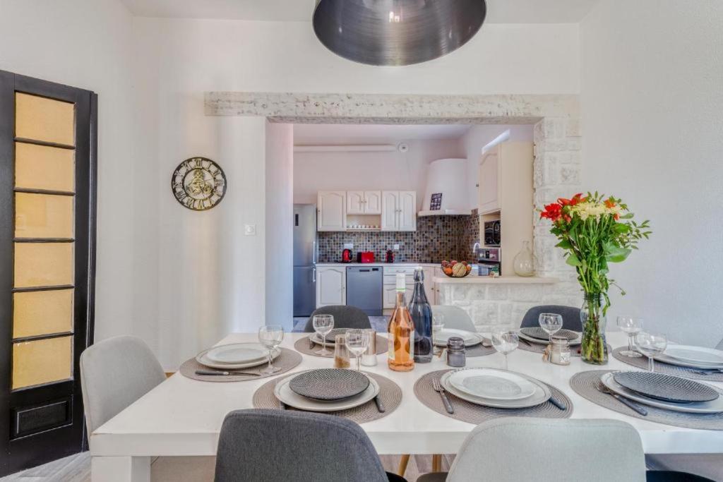 a white dining room table with chairs and a kitchen at L&#39;Ardeche en Provence avec jardin ombragé in Pont-Saint-Esprit