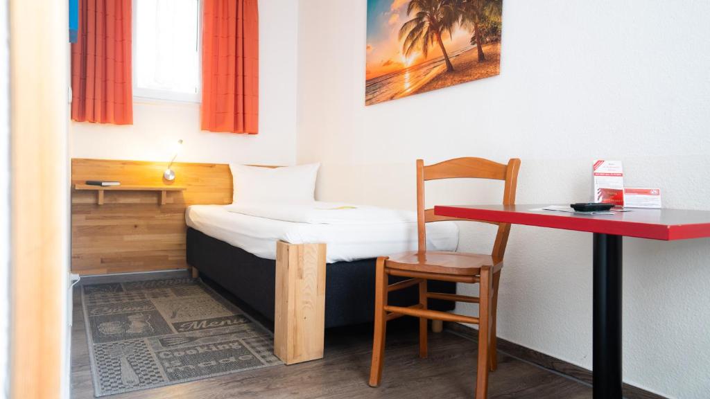 Kleines Zimmer mit einem Bett und einem Tisch in der Unterkunft Aalreuse in Rostock
