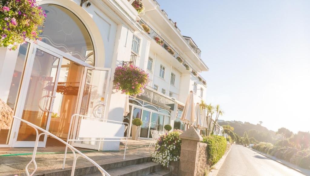 a large white building with flowers on the side of a street at St Brelade's Bay Hotel in St. Brelade