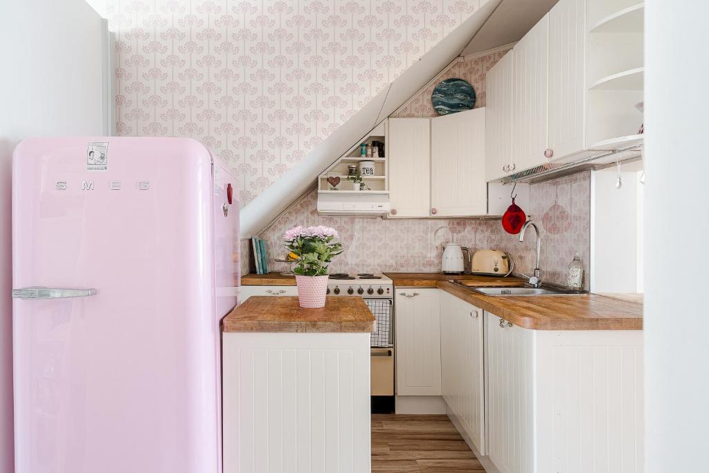 La cuisine est équipée de placards blancs et d'un réfrigérateur blanc. dans l'établissement Unique wooden house apartment with separate office room, à Turku