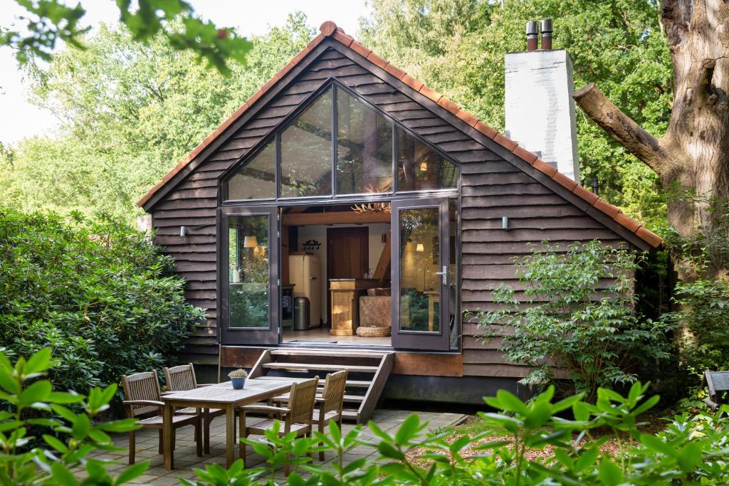 een klein huis met glazen deuren en een tafel bij Landgoed Dennenholt - 5 unique holiday homes in Vierhouten