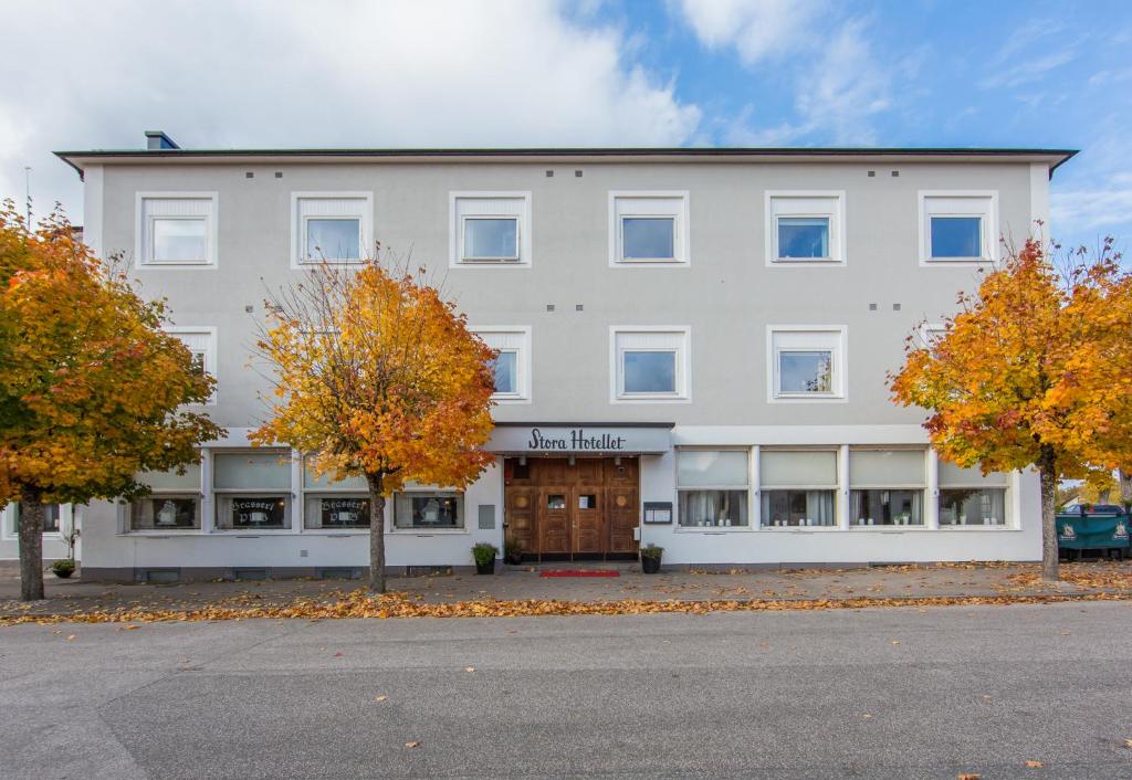 um grande edifício branco com árvores em frente em Stora Hotellet Markaryd em Markaryd