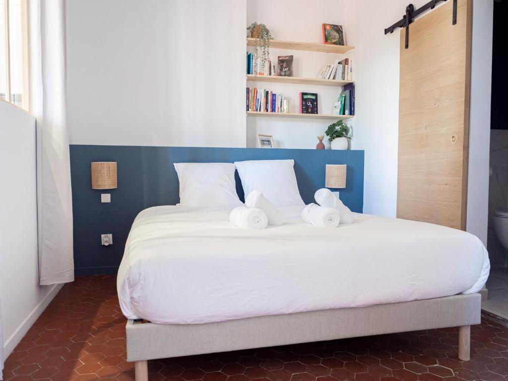 um quarto com uma grande cama branca com almofadas brancas em Le Cocoon - Appartement cocooning à Orange em Orange