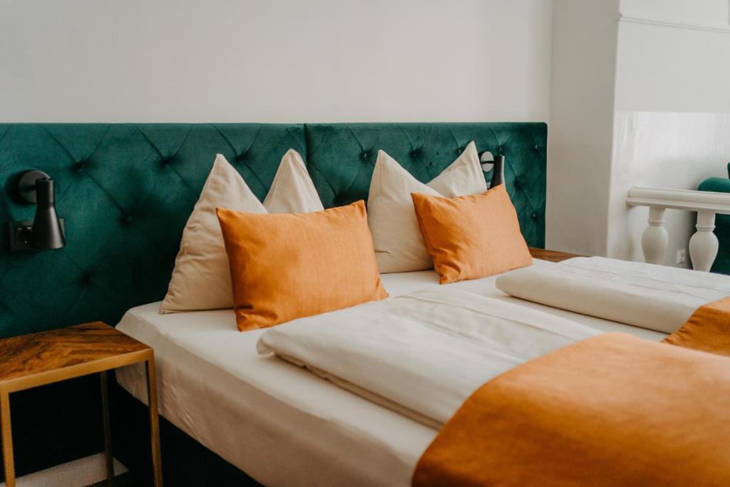 2 Betten mit orangefarbenen und weißen Kissen darauf in der Unterkunft Hotel Palais26 in Villach