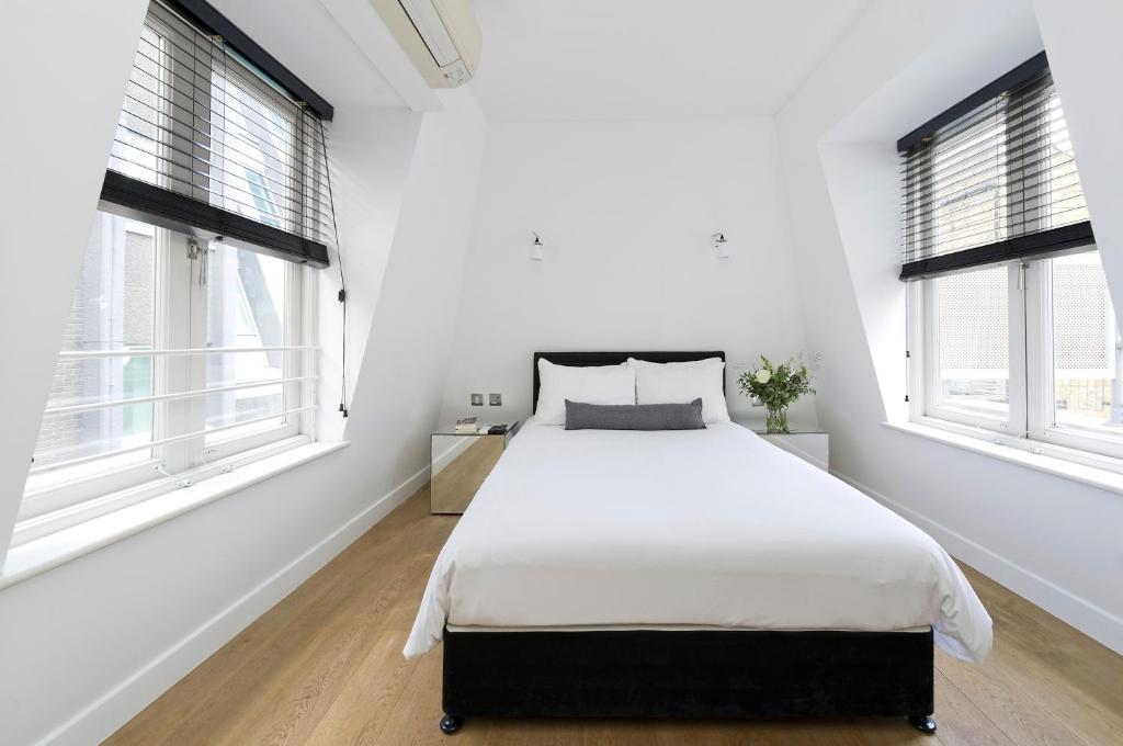 a white bedroom with a large bed and two windows at Crane Court by City2Stay in London